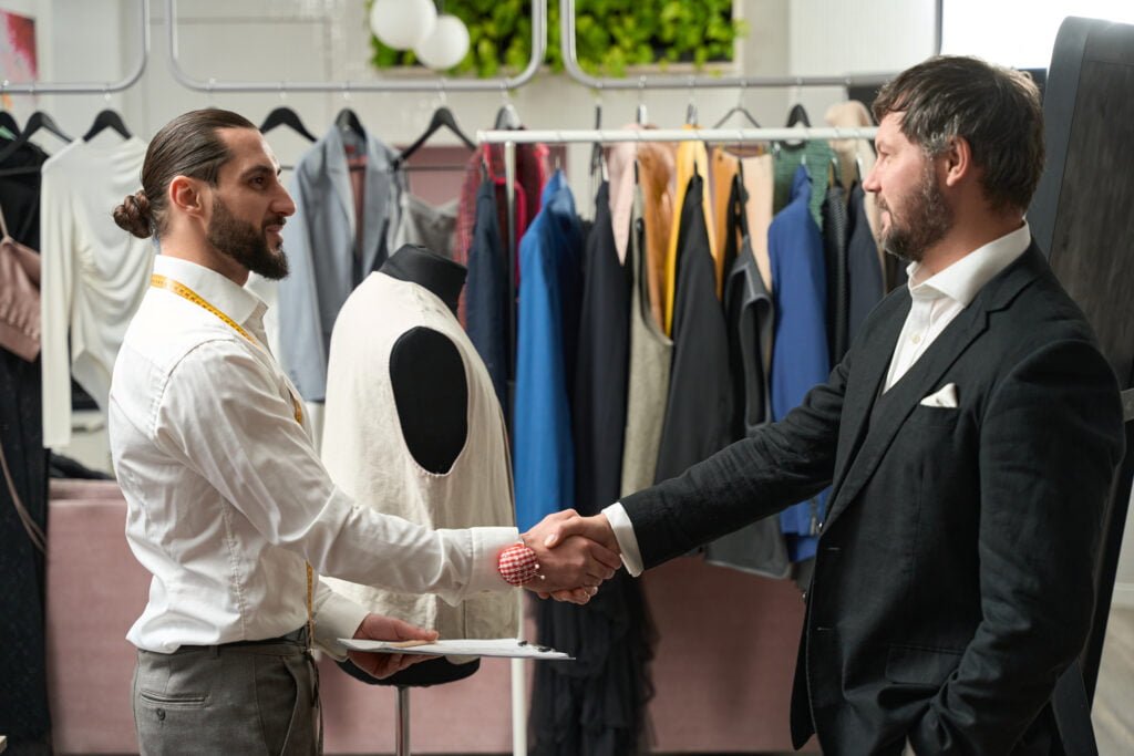 Smiling Friendly Clothier Greeting Client In Studio